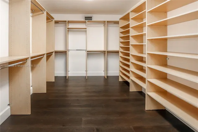 an empty room with wooden floor and fan