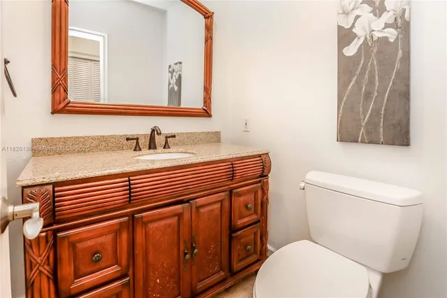 a bathroom with a granite countertop sink a toilet and mirror