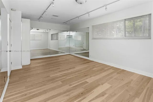 a view of empty room with wooden floor and fan