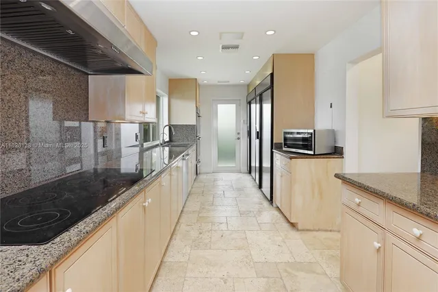 a large white kitchen with a large window and stainless steel appliances