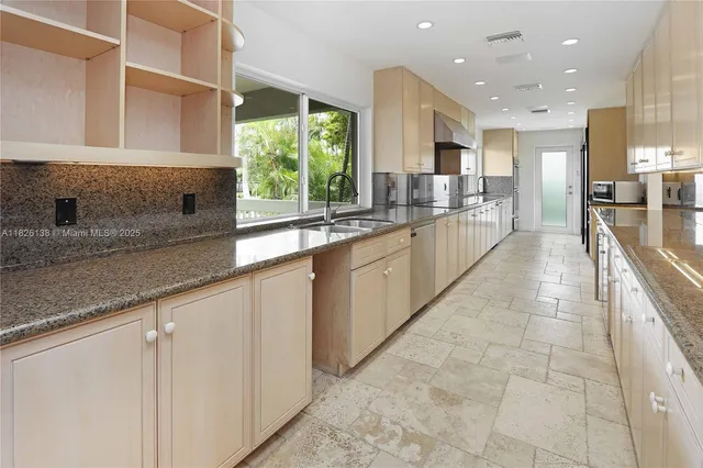 a large kitchen with stainless steel appliances kitchen island granite countertop a refrigerator and a sink