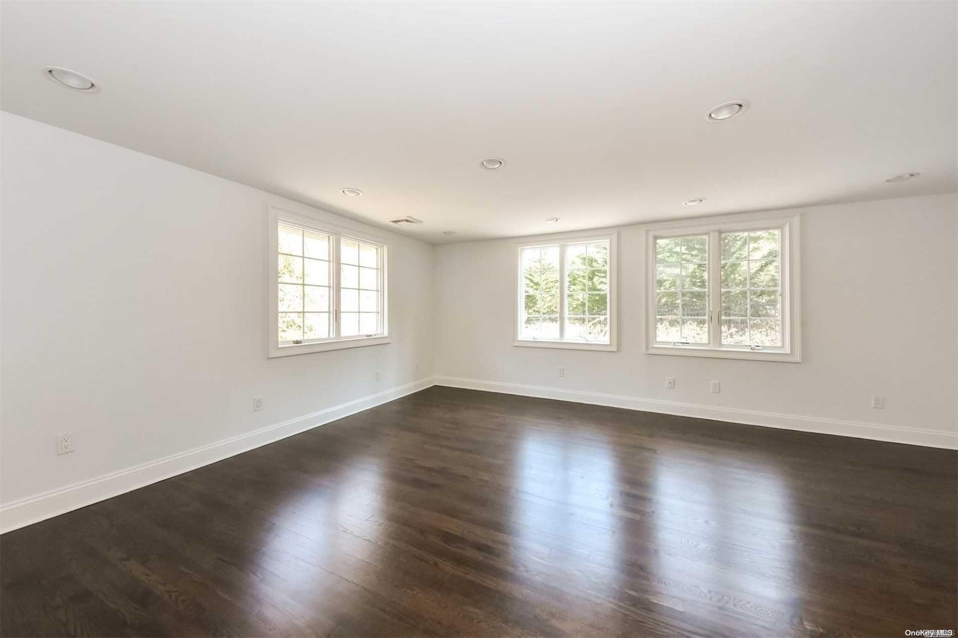 1 Parish Drive Locust Valley, NY 11560 - Photo 11 of 19 an empty room with wooden floor and windows