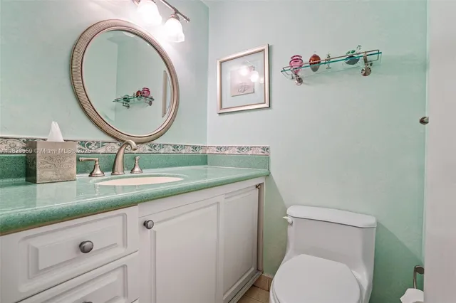 a bathroom with a granite countertop toilet sink vanity and mirror