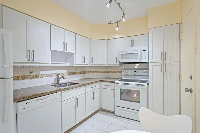 a kitchen with white cabinets white appliances sink and dishwasher