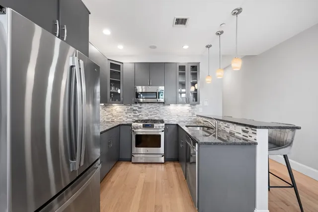 a kitchen with kitchen island a counter top space a sink stainless steel appliances and cabinets