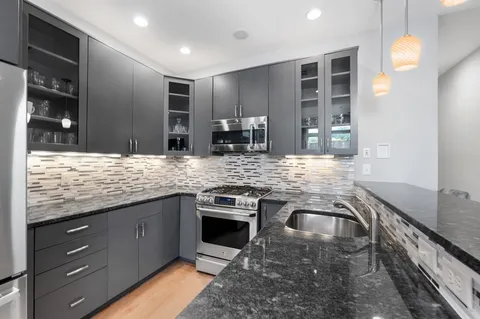 a kitchen with stainless steel appliances granite countertop sink stove and cabinets