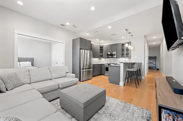 a living room with stainless steel appliances furniture and a flat screen tv