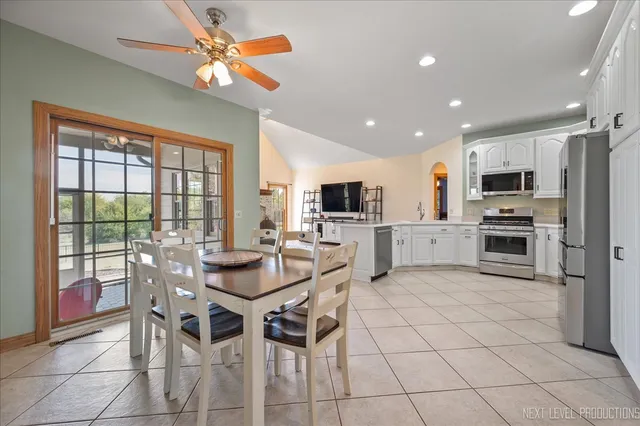 a kitchen with stainless steel appliances kitchen island granite countertop a stove top oven a sink a dining table and chairs