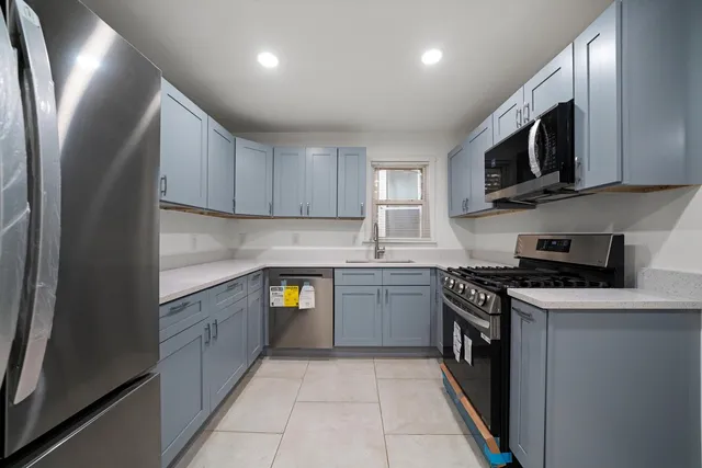 a kitchen with stainless steel appliances granite countertop a sink a stove top oven and a refrigerator