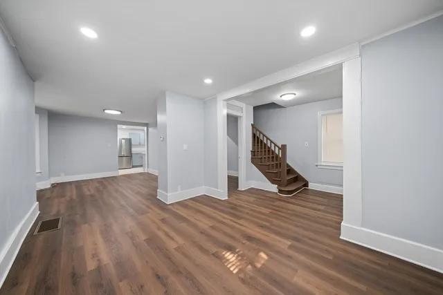a view of an empty room with wooden floor and stairs