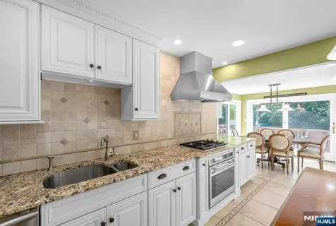 a kitchen with granite countertop a sink a stove and cabinets