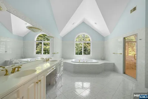 a spacious bathroom with a tub sink and mirror