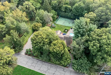 an aerial view of residential house with outdoor space and trees all around