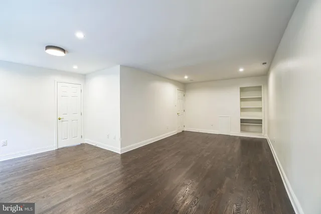 a view of an empty room with wooden floor and closet