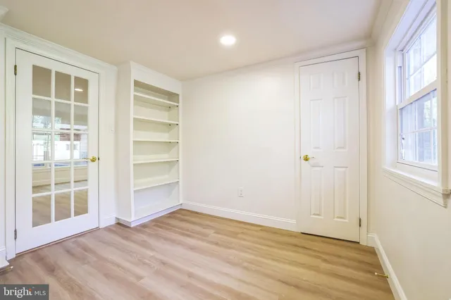 a view of an empty room with wooden floor and windows