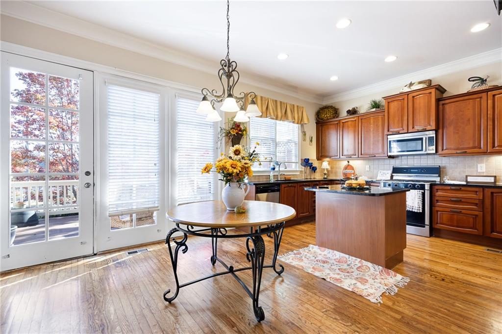 2354 St Davids Square, Unit 3 Kennesaw, GA 30152 - Photo 12 of 39 a kitchen with stainless steel appliances granite countertop a refrigerator a stove a sink dishwasher and a dining table with wooden floor