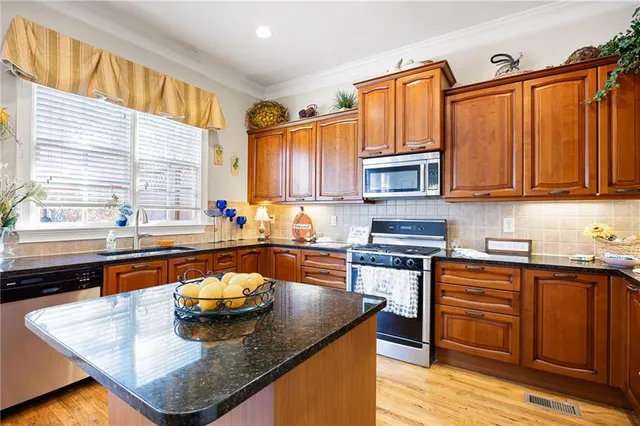 a kitchen with stainless steel appliances granite countertop a sink a stove counter space and a window