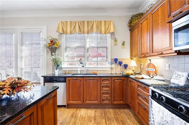 a kitchen with stainless steel appliances granite countertop wooden cabinets and a stove top oven