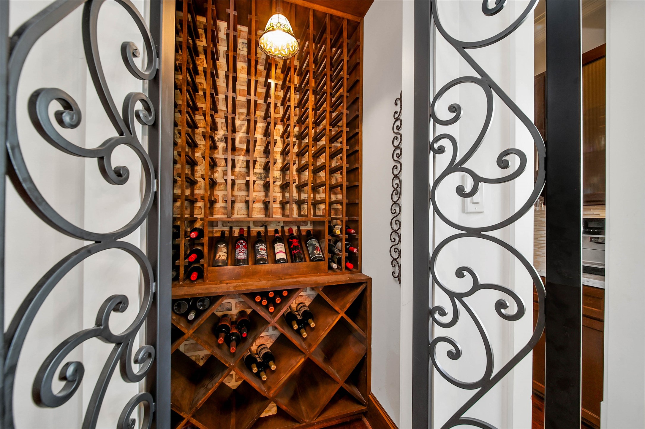 416 West 33rd Street Houston, TX 77018 - Photo 16 of 47 Perfectly positioned at the end of the dining room, this stunning wine room showcases custom wood wine storage framed by striking wrought iron doors, creating a warm and sophisticated focal point ideal for entertaining and displaying a curated collection.