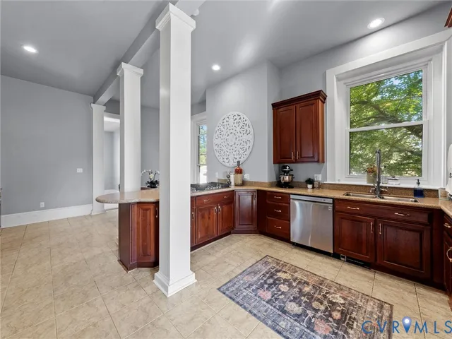 a large kitchen with stainless steel appliances granite countertop wooden cabinets a stove a sink and a large window