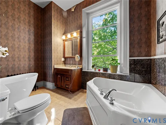 a bathroom with a tub sink toilet window and mirror