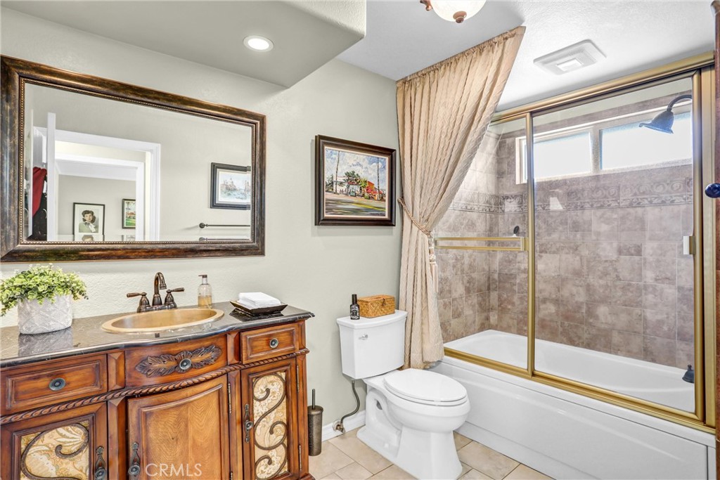 5787 Ridgeway Road Rancho Cucamonga, CA 91701 - Photo 35 of 56 a bathroom with a granite countertop sink a toilet a mirror and a shower