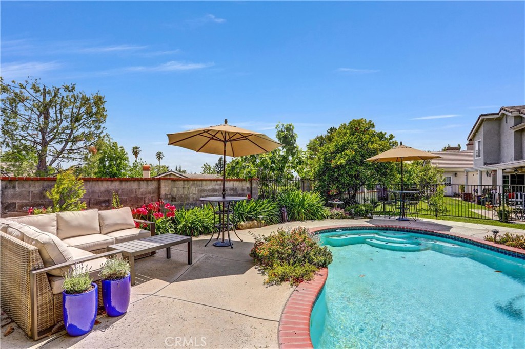 5787 Ridgeway Road Rancho Cucamonga, CA 91701 - Photo 42 of 56 a view of a patio with couches table and chairs under an umbrella with a small yard