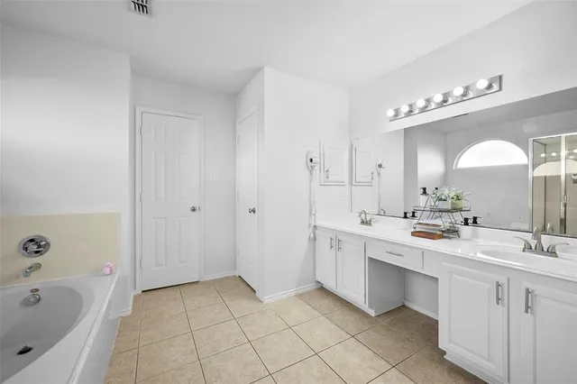 a spacious bathroom with a double vanity sink mirror and bathtub