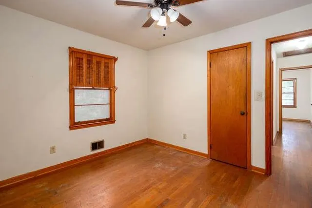 an empty room with a window and ceiling fan