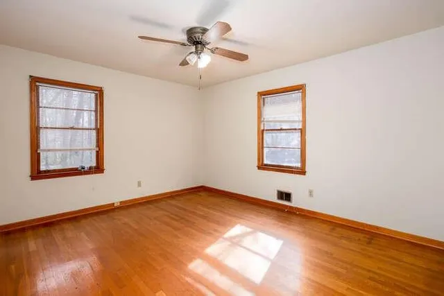 a view of an empty room window and wooden floor
