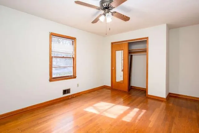 an empty room with windows and fan