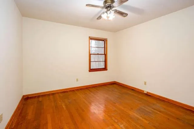 an empty room with windows and fan