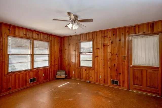an empty room with windows closet and chandelier fan