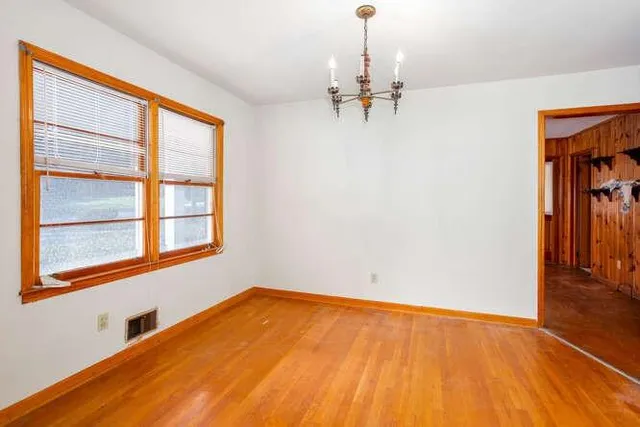 a view of empty room with a window and wooden floor