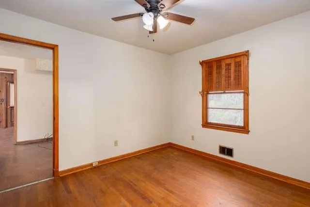 an empty room with a window and a ceiling fan