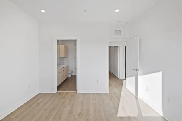 a view of an empty room with wooden floor and a bathroom