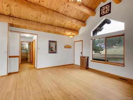 a view of an empty room with a window and wooden floor