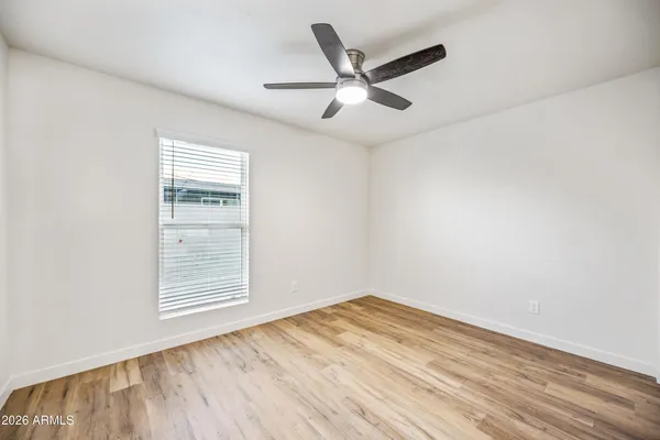 an empty room with wooden floor fan and windows