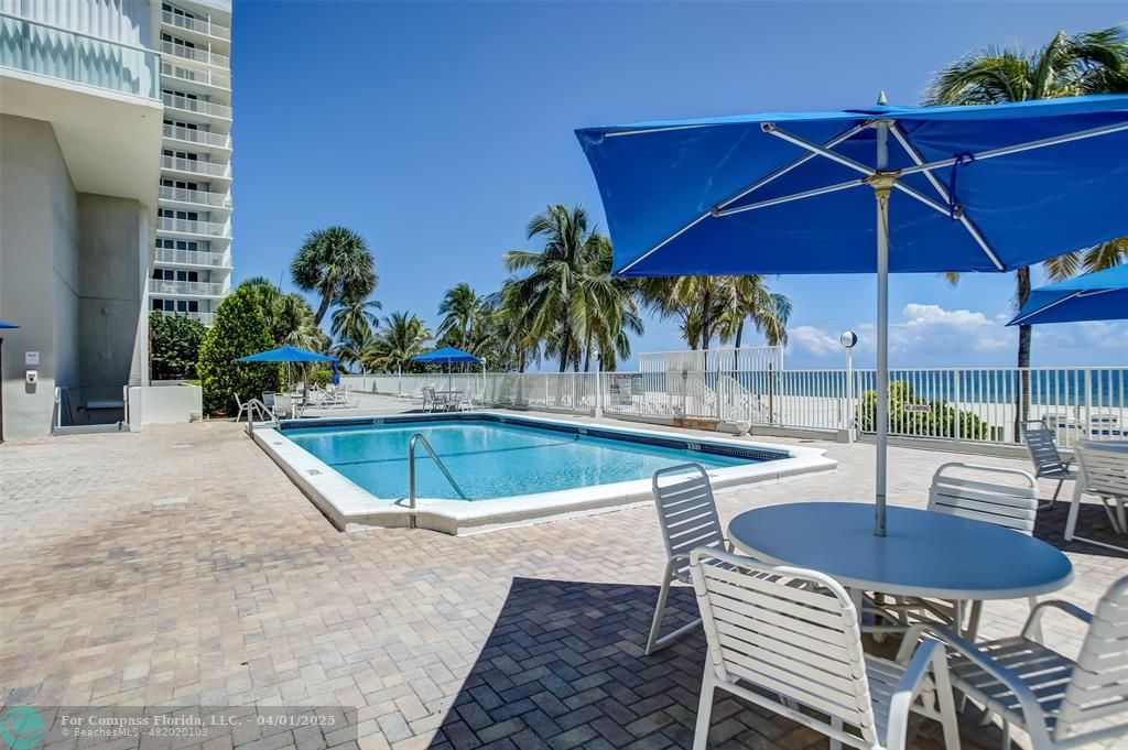 1000 South Ocean Boulevard, Unit 5O Pompano Beach, FL 33062 - Photo 31 of 42 a view of a swimming pool with a table and chairs under an umbrella