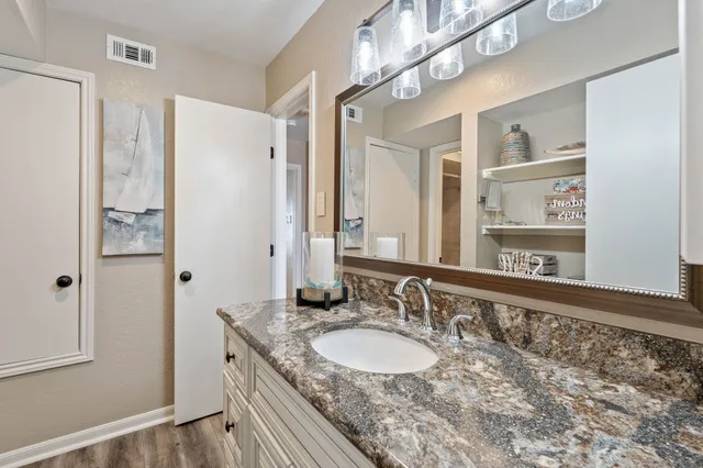 a bathroom with a granite countertop sink a mirror and a shower