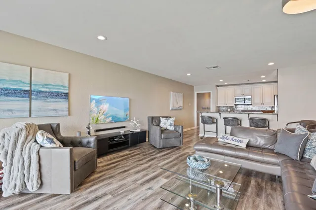 a living room with furniture kitchen view and a large window