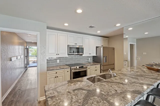 a kitchen with stainless steel appliances granite countertop a stove top oven a sink and a refrigerator