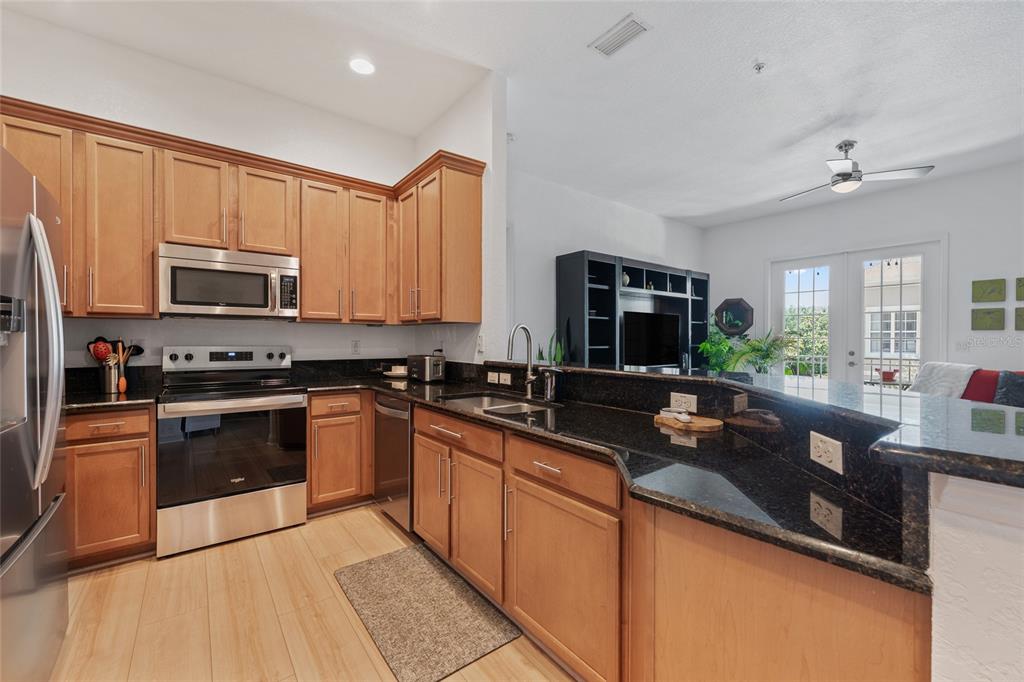 1819 Common Way Road, Unit 203 Orlando, FL 32814 - Photo 8 of 23 a kitchen with stainless steel appliances granite countertop a sink a stove top oven a refrigerator cabinets and a dining table