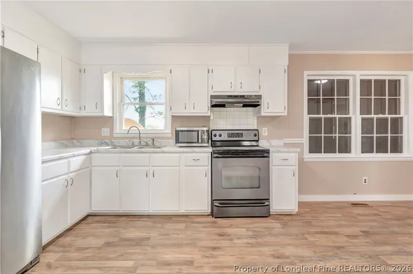 a kitchen with granite countertop white cabinets and appliances