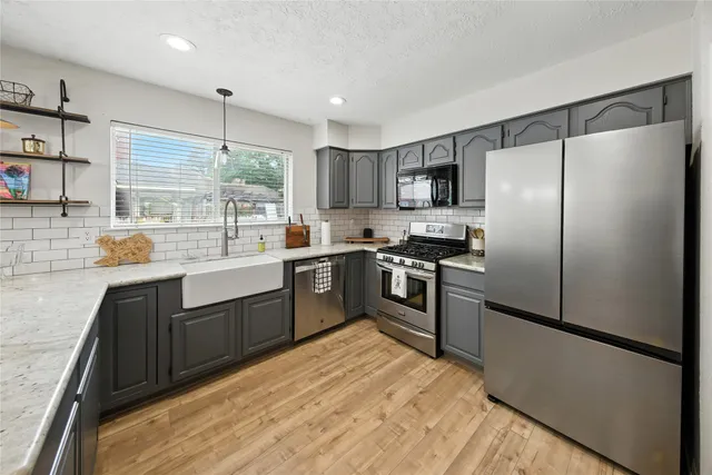 a kitchen with granite countertop stainless steel appliances a refrigerator sink and microwave