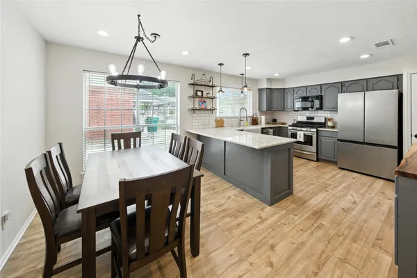 a kitchen with stainless steel appliances kitchen island granite countertop a table chairs and a refrigerator