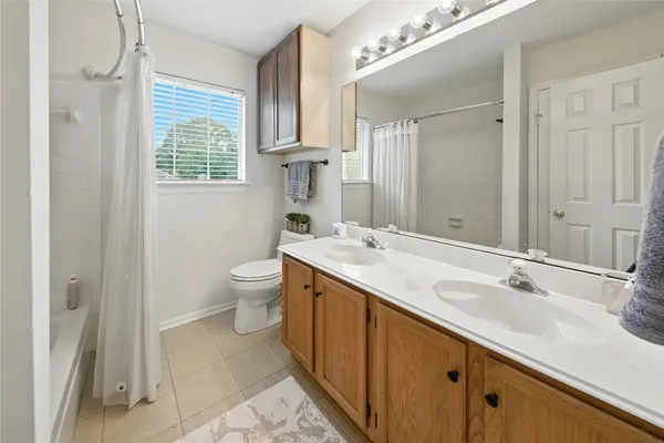 a spacious bathroom with a double vanity sink toilet and a mirror