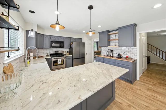 a kitchen with stainless steel appliances granite countertop a sink a stove and a wooden floor