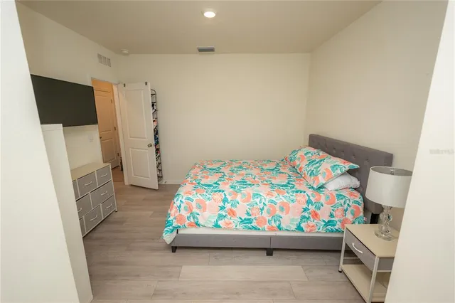a view of a swimming pool with lawn chairs potted plants and palm tree