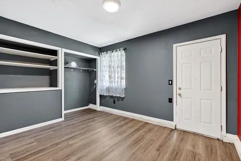 a view of an empty room with wooden floor and a window